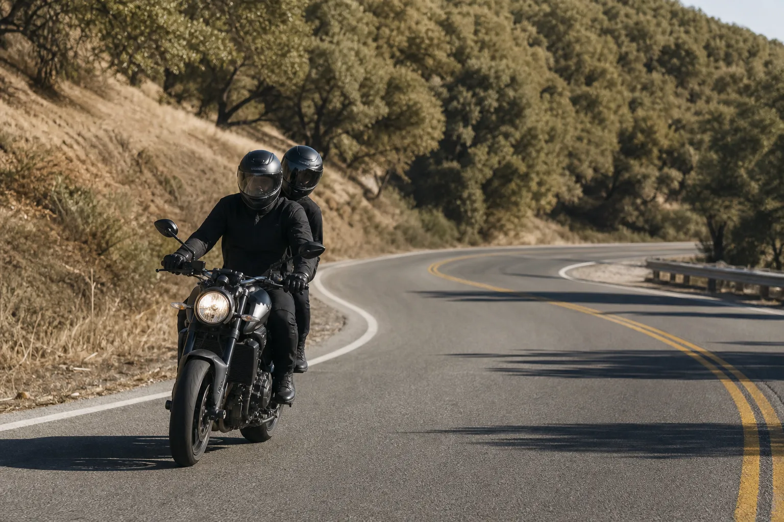 Two riders traveling conservatively on a quiet dry road.