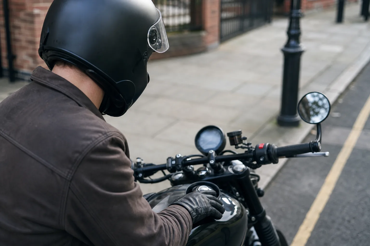 Gloved rider observing an out-of-focus motorcycle instrument panel.