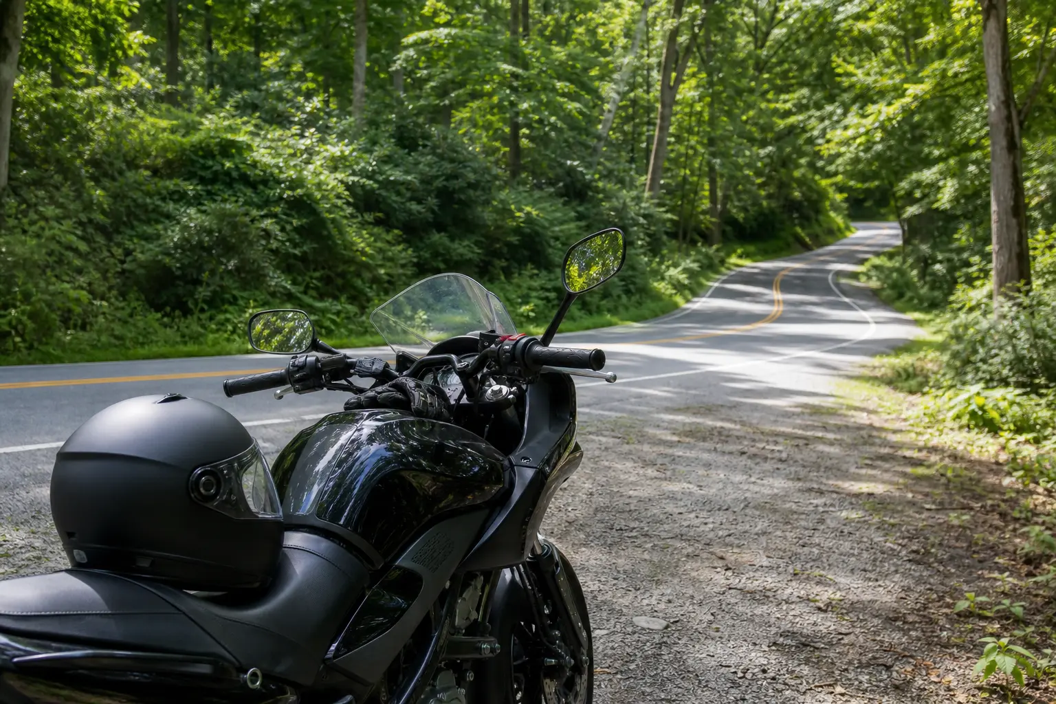 A shaded rural motorcycle route with a blind bend and limited sightline.