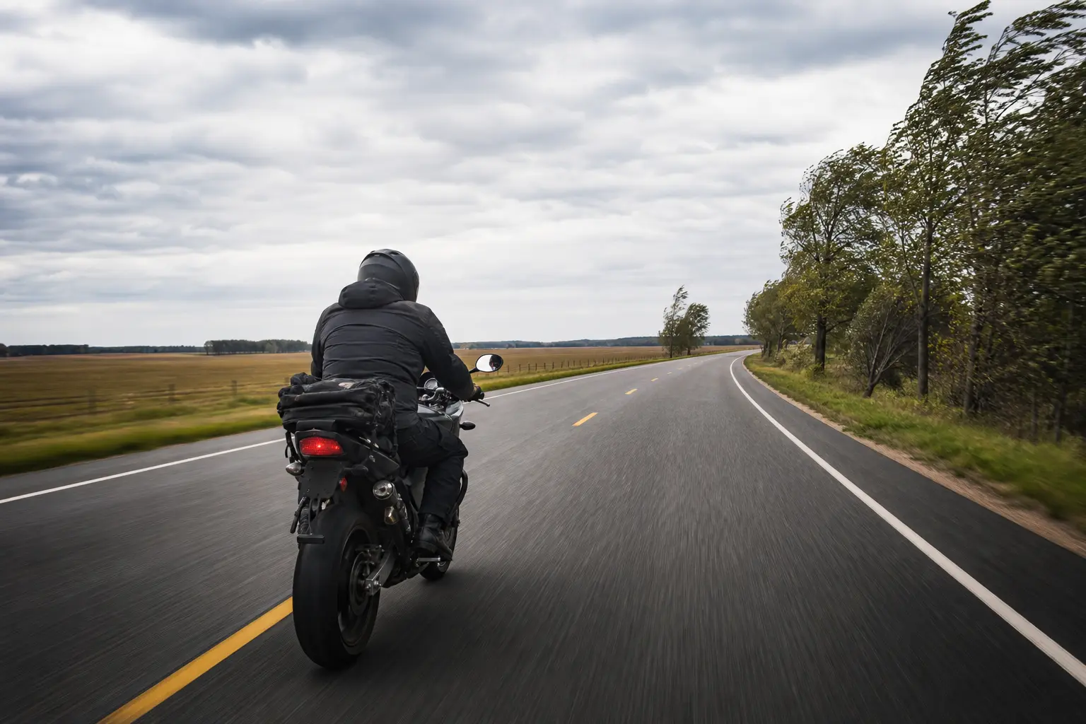 Motorcyclist preserving lane margin while riding in a crosswind.