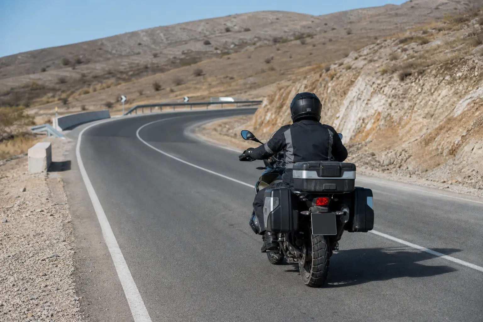 Motorcyclist scanning ahead on a paved ramp with loose material near the edge.